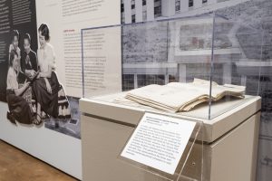 A large stack of UW student petitions protesting housing discrimination in the 1950s is showcased atop a stone pedestal as part of the “Sifting and Reckoning: UW–Madison’s History of Exclusion and Resistance” exhibit at the Chazen Museum of Art at the University of Wisconsin–Madison.