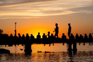 Students and campus community members watch the sunset on Goodspeed Family Pier near the Memorial Union Terrace during an early spring evening at the University of Wisconsin–Madison.