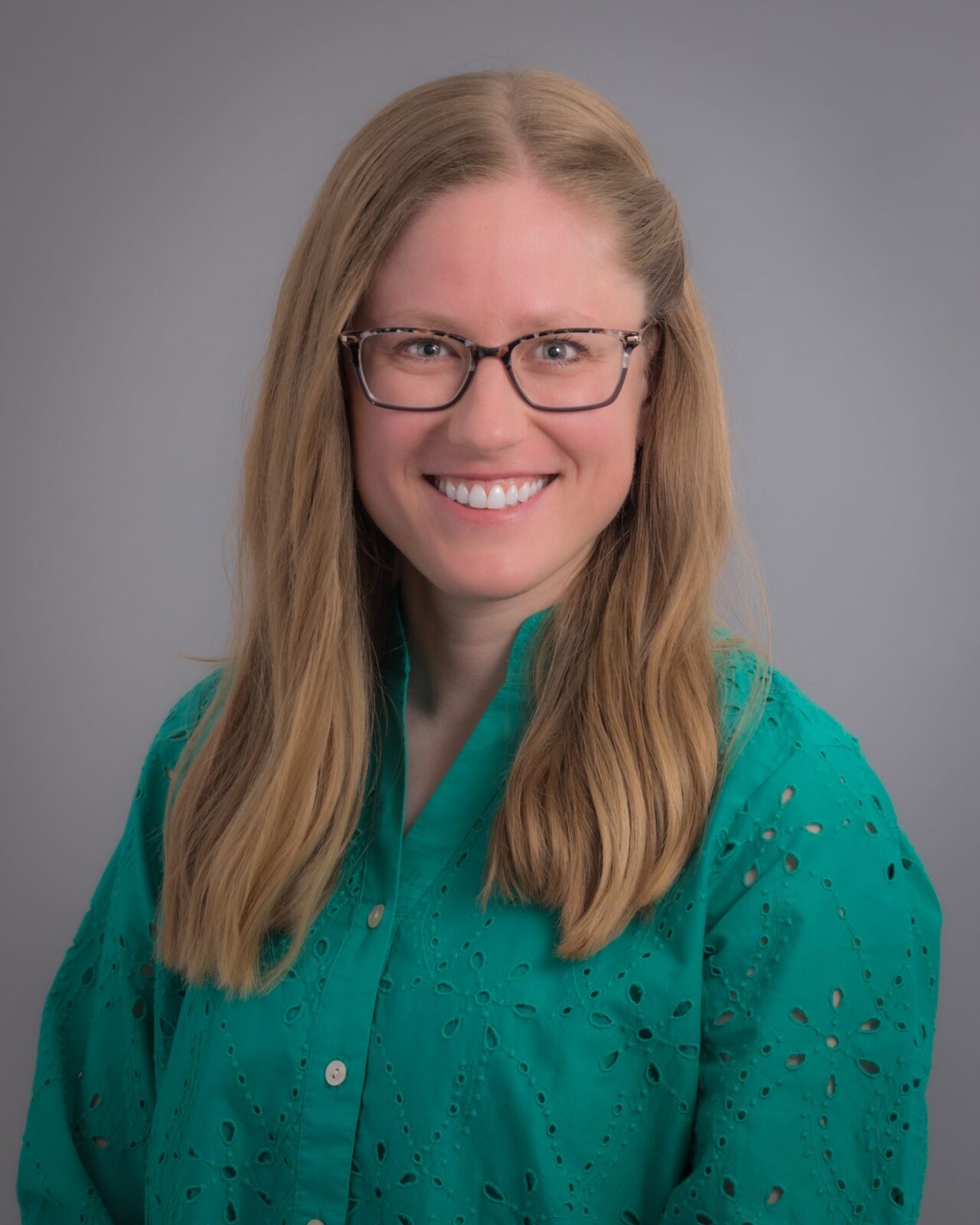 Lindsey Peterson, smiling woman with blonde hair wearing glasses and a green shirt.